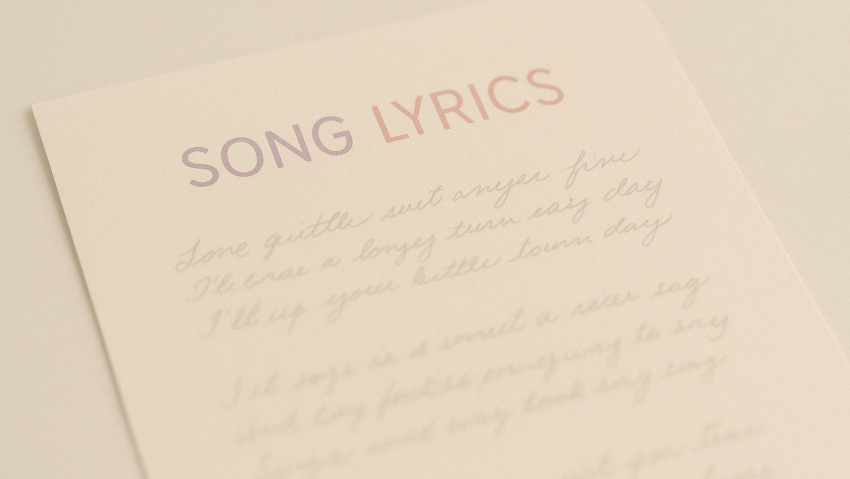 a softly lit piece of paper has the words song lyrics at the top with indistinguishable handwritten words below